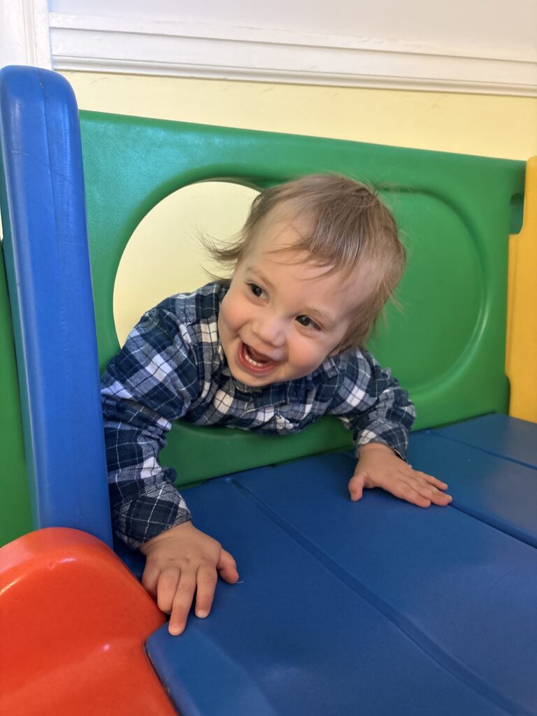 A toddler smiling while playing in the church nursery